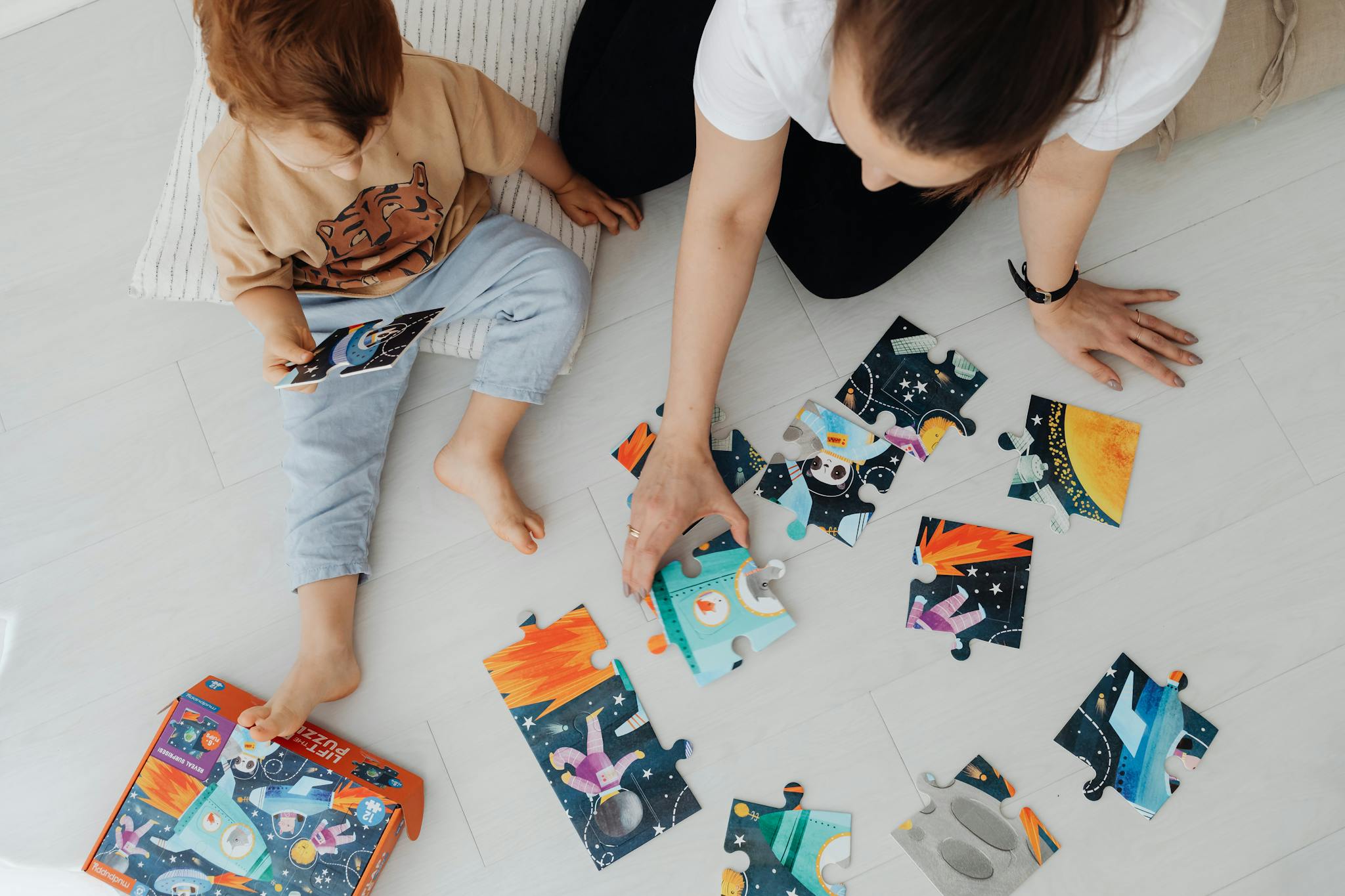 A mother and child bonding over a colorful puzzle on the floor, enjoying quality time together.