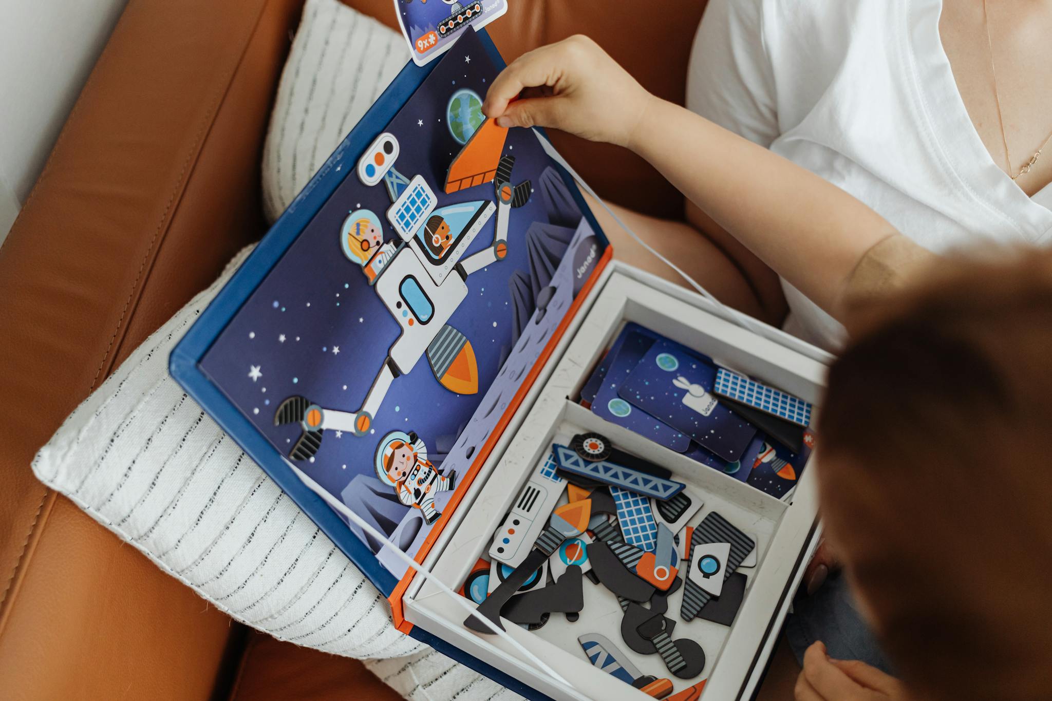 Child engaged in assembling a colorful space-themed puzzle indoors.